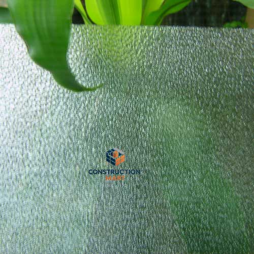 Transparent raindrop-textured polycarbonate sheet by Constructionmart used for commercial lighting projects, photographed with plants in the background to highlight its clarity and light diffusion.