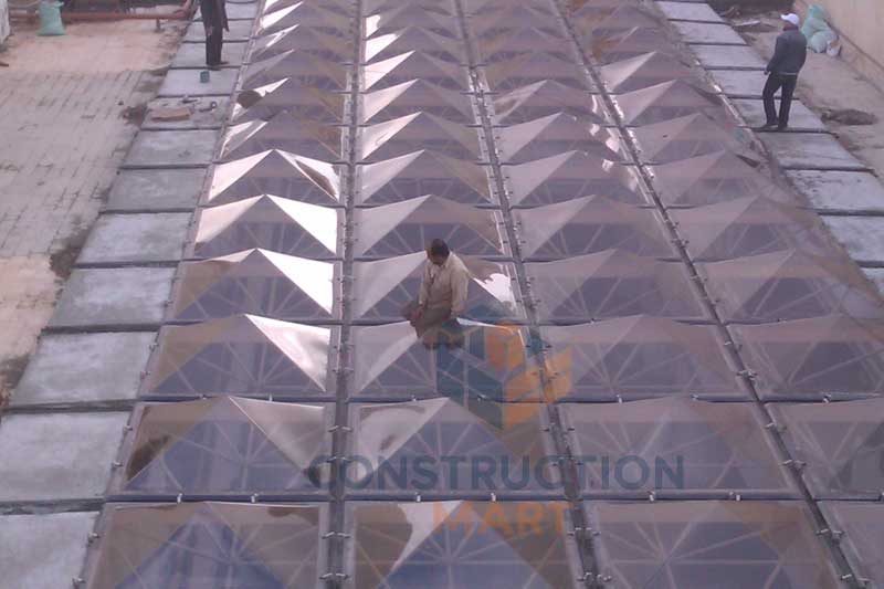 Pointed-top polycarbonate skylight by Constructionmart installed on a building, showing its practical application with a person on the structure for scale.