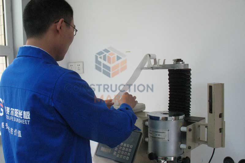 Constructionmart staff performing product quality inspection on a testing machine, carefully monitoring data to ensure product accuracy and reliability