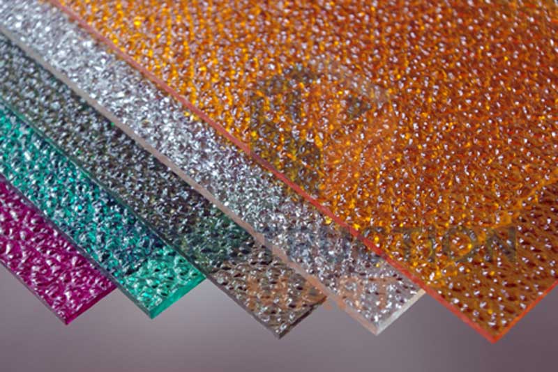 Colorful raindrop-pattern embossed polycarbonate sheet, photographed at an angle to highlight the unique surface texture and decorative light effect