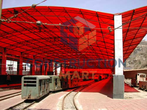 Industrial factory canopy with red polycarbonate sheet covering railway tracks for weather protection