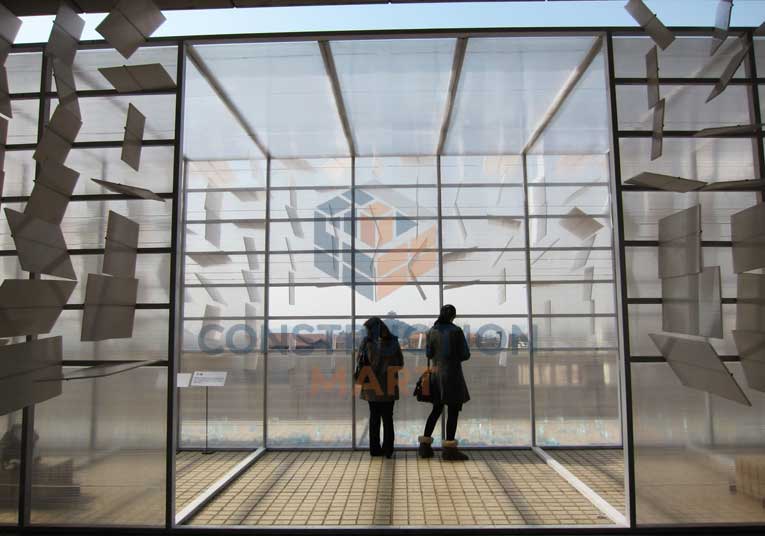 Two people standing inside a modern exhibition hall built with twin-wall polycarbonate sheets as roof and wall panels, showcasing creative architectural glazing design